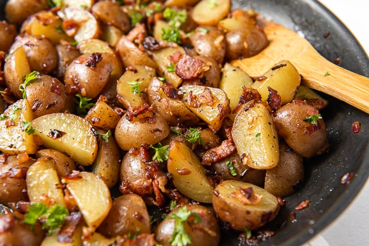 German potato salad in a skillet with a wooden spoon