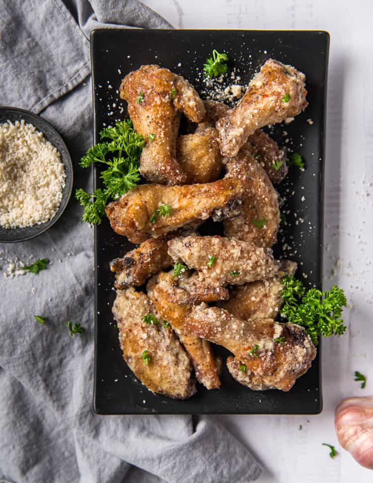 Air Fryer chicken wings tossed in garlic parmesan sauce on a plate
