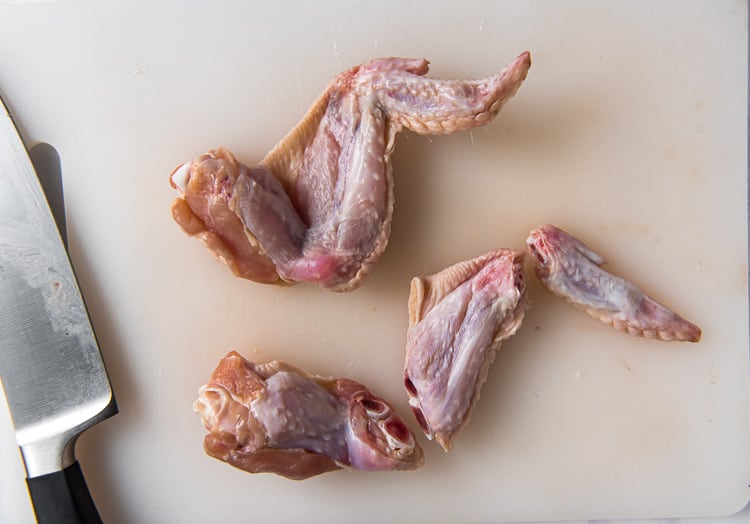 A raw, cut chicken wing showcasing the 3 parts, the drummette, flat, and tip