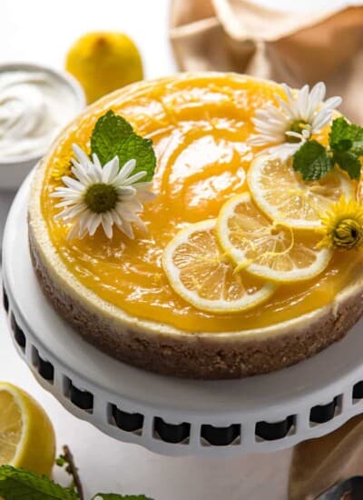 an Instant Pot Lemon Ricotta Cheesecake on a cake stand