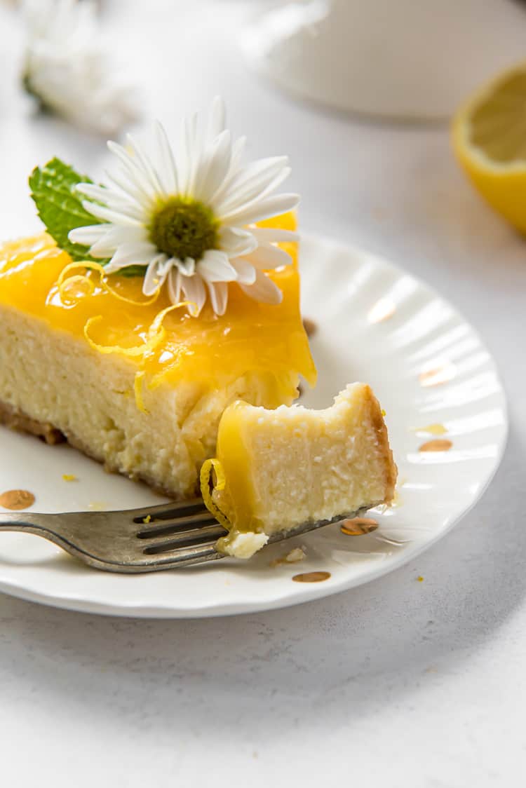 A slice of lemon ricotta cheesecake on a plate with a bite taken out