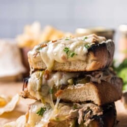 A stack of open-faced tuna melt sandwiches with potato chips