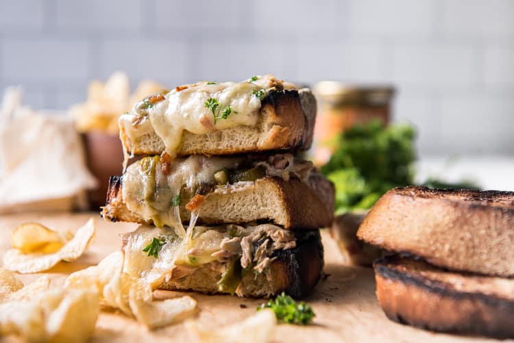 A stack of open-faced tuna melt sandwiches with potato chips