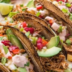 Raspberry Chipotle Slow Cooker Chicken Tacos garnished with raspberries and avocado