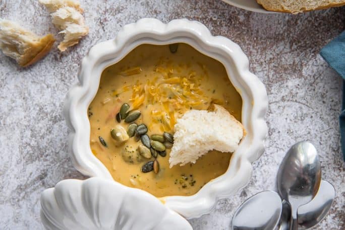 pumpkin broccoli cheddar soup in a white ceramic pumpkin-shaped bowl