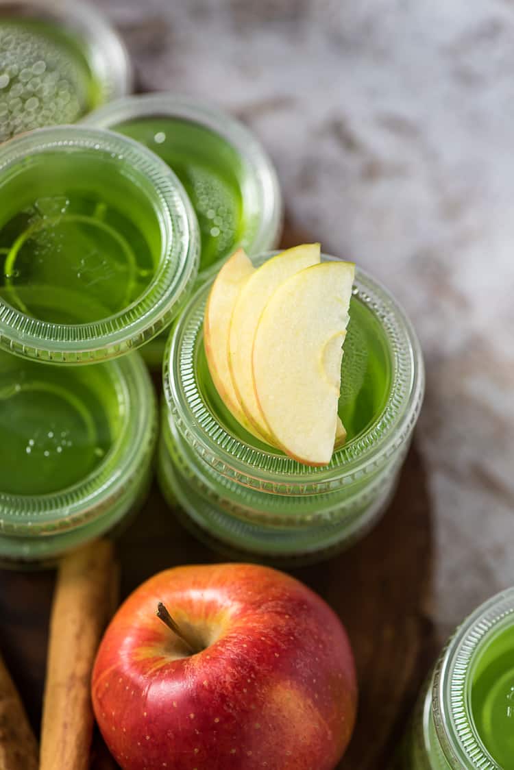stacks of green jello shots with apple slices on top
