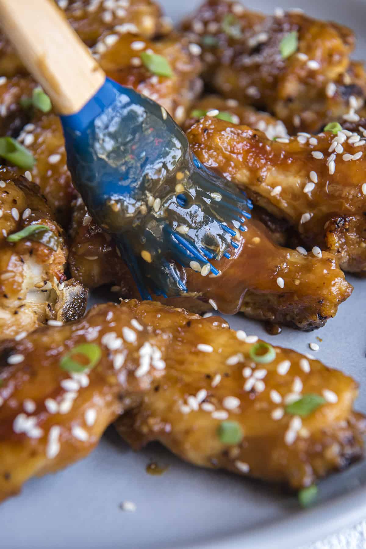 chicken wings being basted with teriyaki sauce