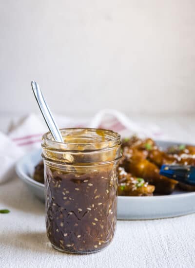 easy teriyaki sauce in a mason jar in front of a platter of chicken wings