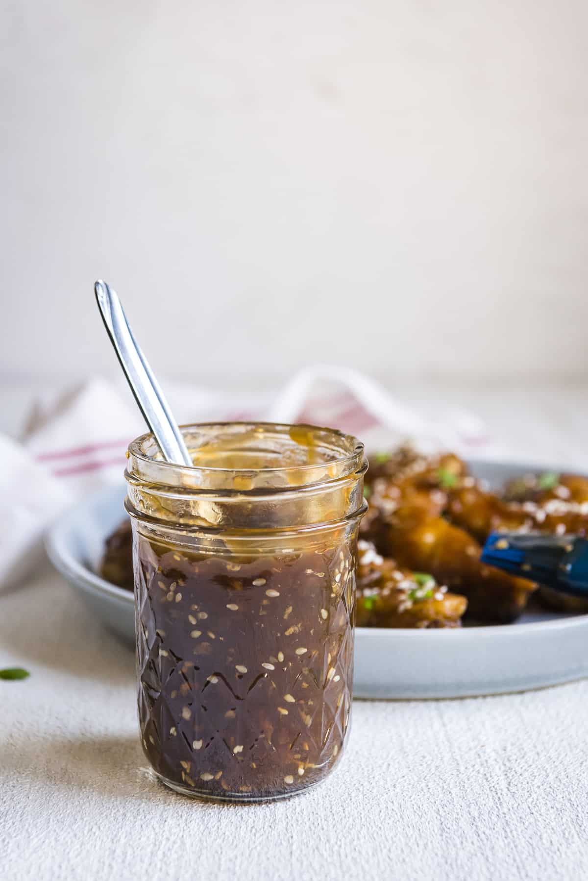 easy teriyaki sauce in a mason jar in front of a platter of chicken wings