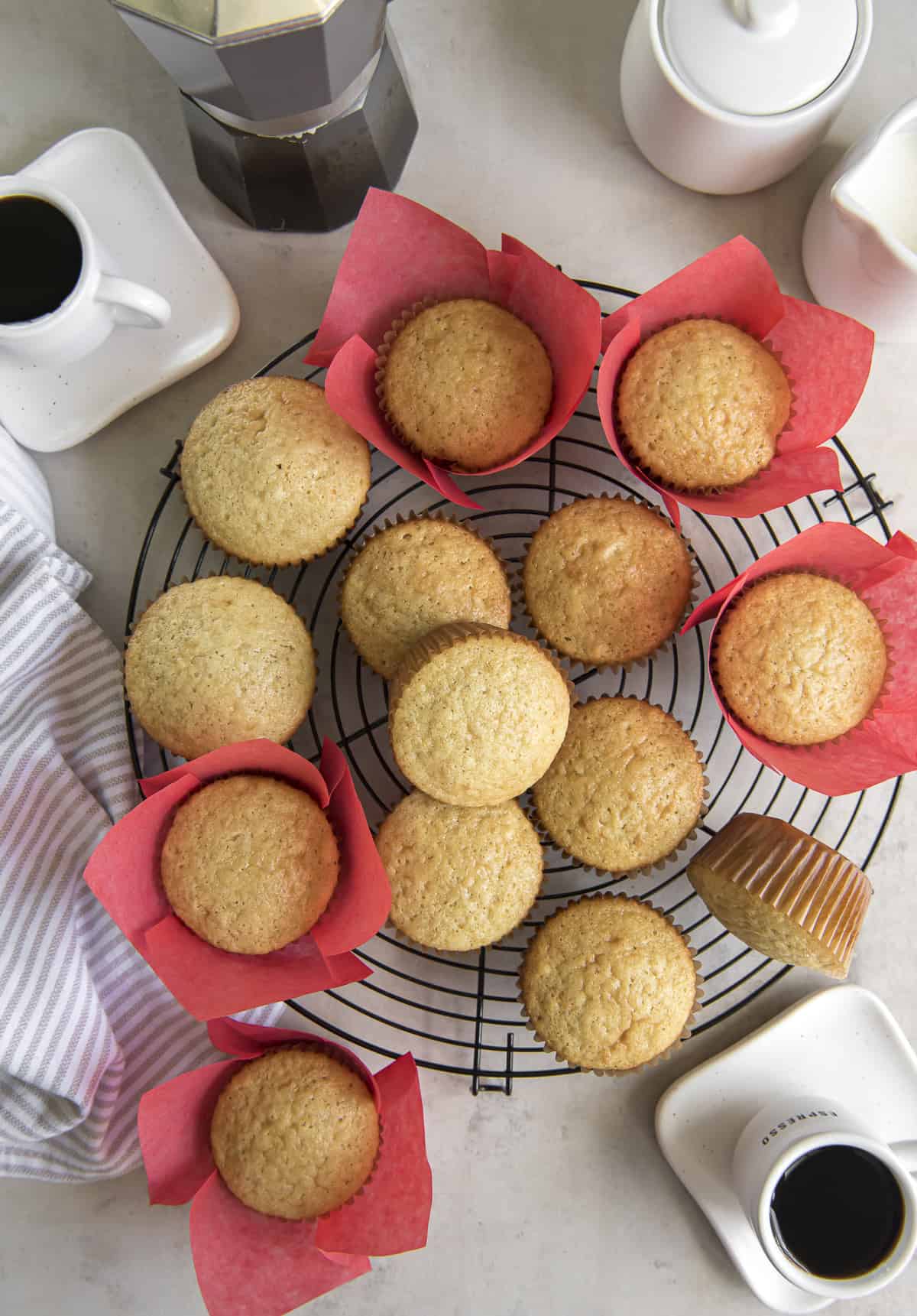 an overhead shot of a cooling rack full of baked Mantecadas Muffins, surrounded by cups of espresso