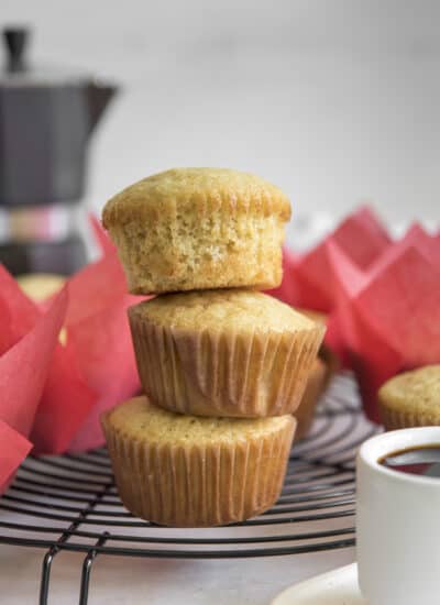 a stack of Mantecadas Muffins in paper liners with an espresso pot in the background
