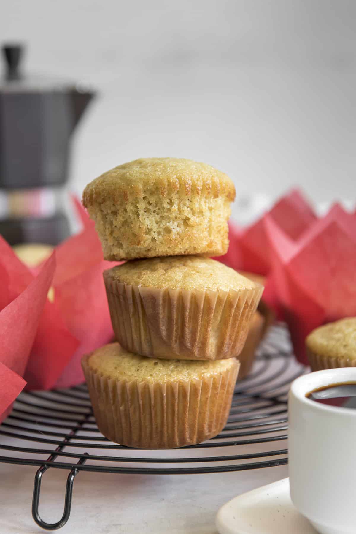 a stack of Mantecadas Muffins in paper liners with an espresso pot in the background