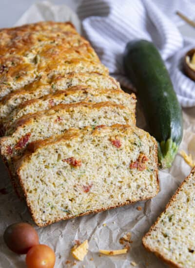 several slices of savory zucchini bread shingled together with veggies surrounding them.