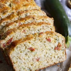 several slices of savory zucchini bread shingled together on parchment paper.