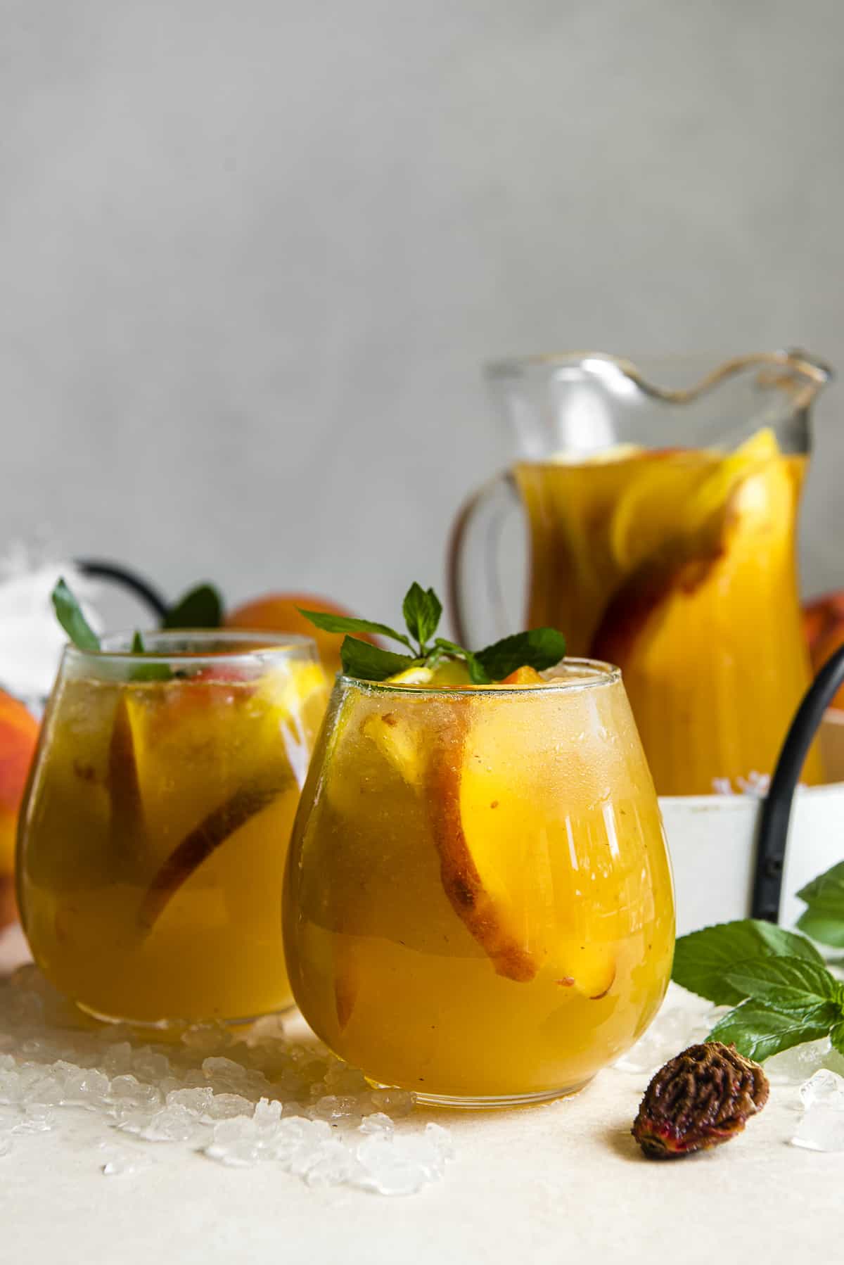 white peach sangria in two wine glasses with a pitcher in the background