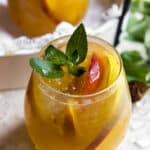 a glass of peach sangria garnished with mint