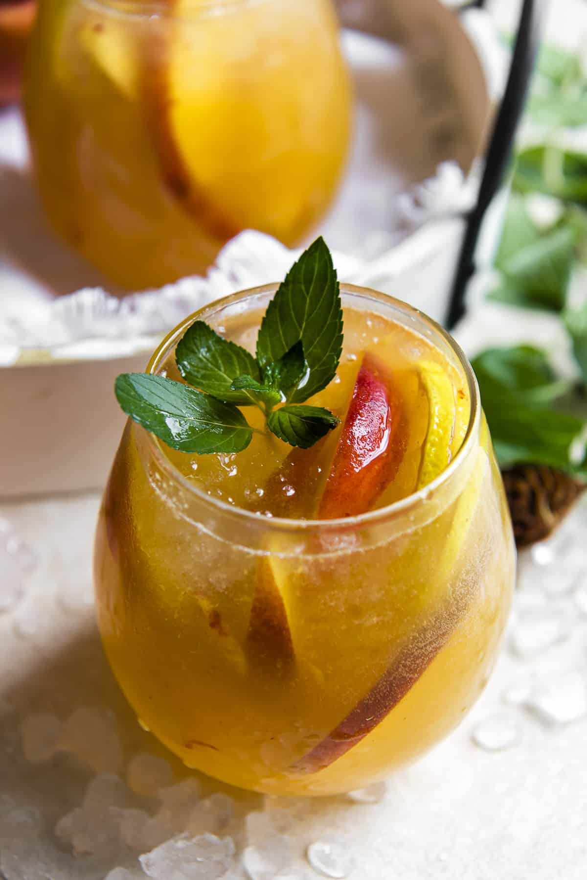 a glass of peach sangria garnished with mint
