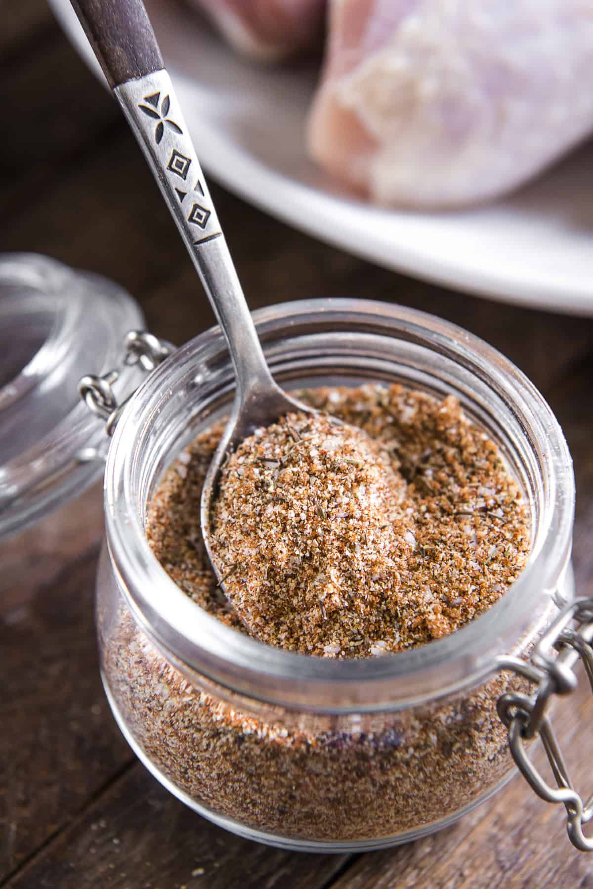 a spoonful of blended smoked chicken rub in a small jar