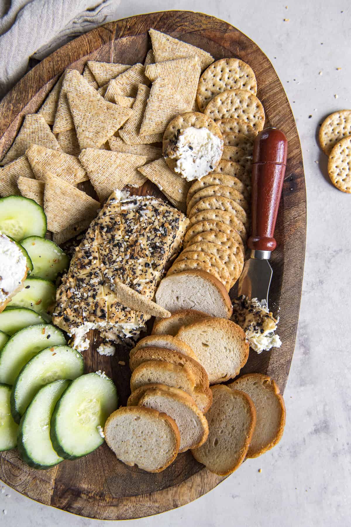 smoked cream cheese on a wooden platter with crackers and cucumbers