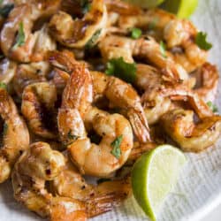 Smoked shrimp on a white plate with lime wedges