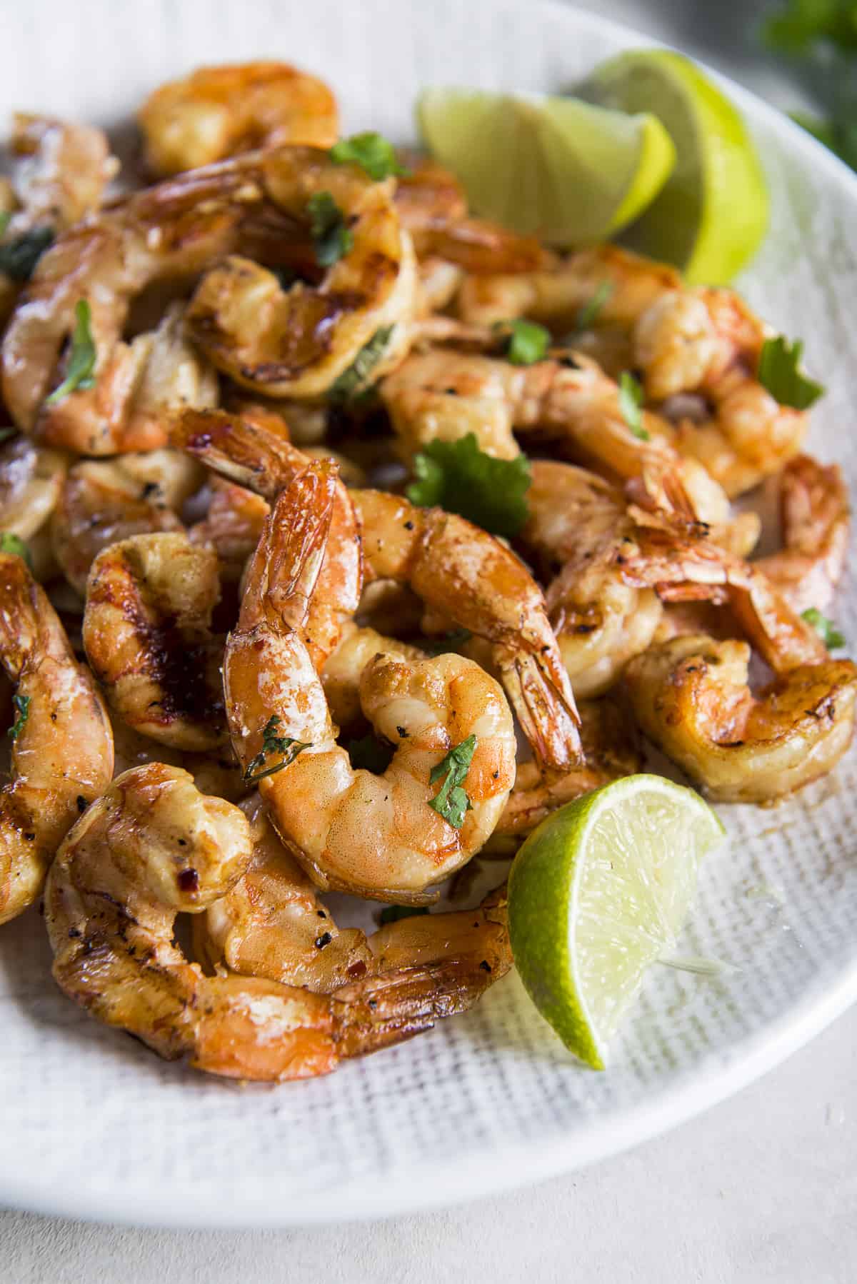 Smoked shrimp on a white plate with lime wedges