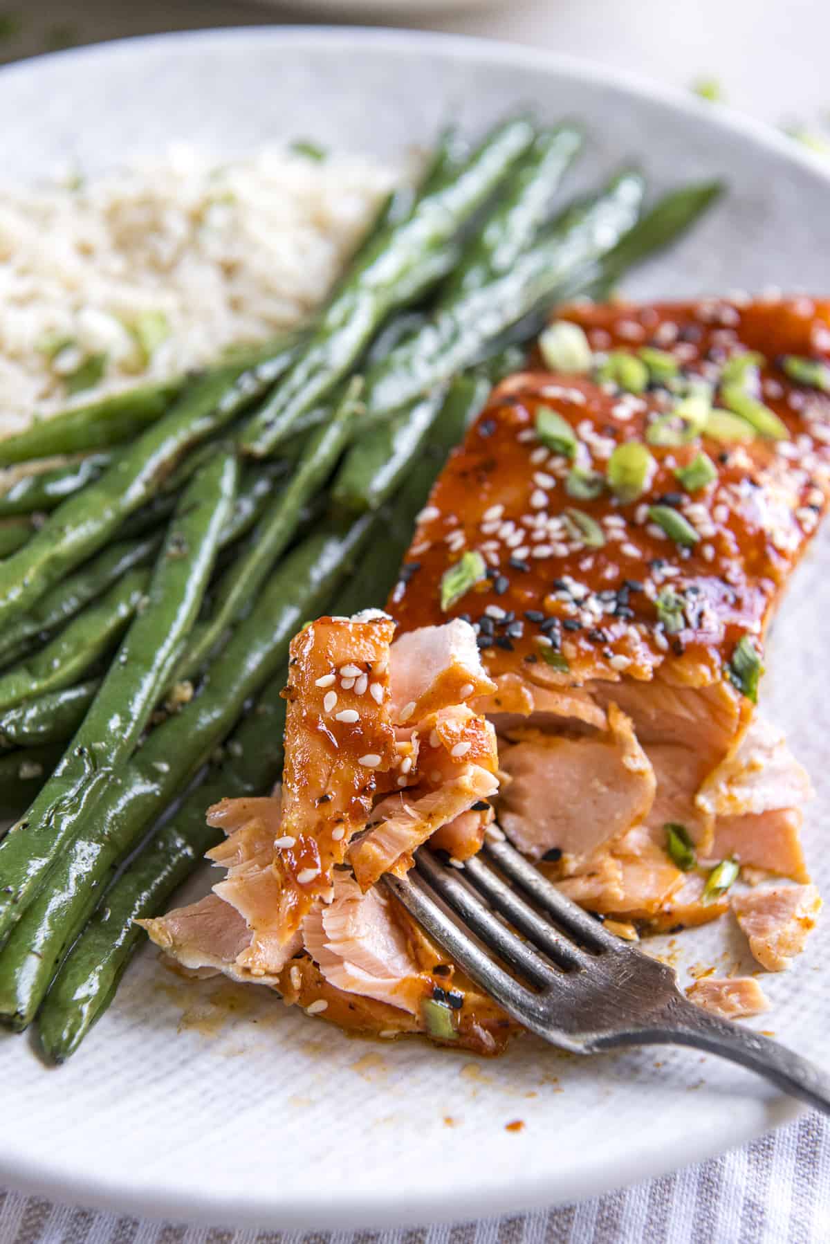 A plate with gochujang salmon and green beans on it.