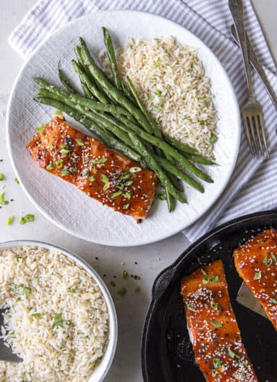A skillet with salmon, green beans, rice and sesame seeds.