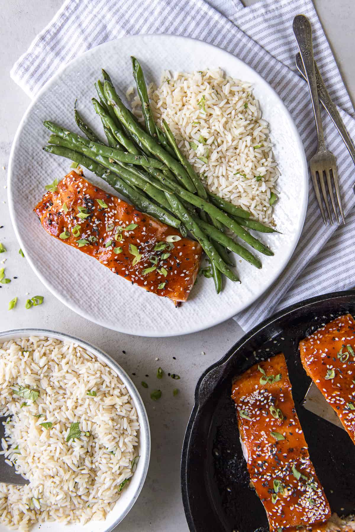 A skillet with salmon, asparagus, rice and sesame seeds.